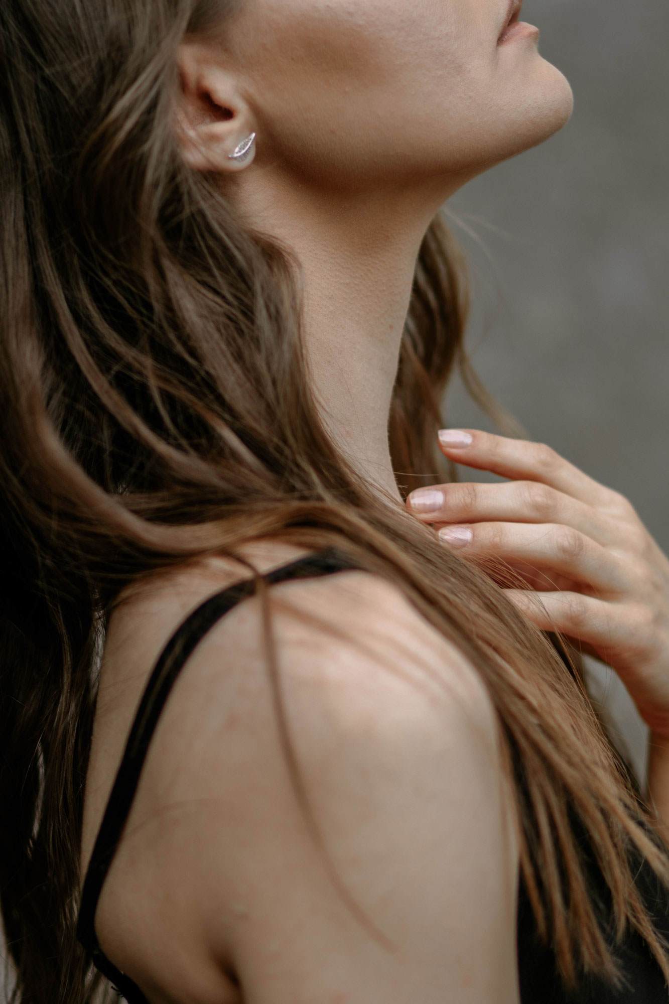 黒いキャミソールを着たブラウンストレートヘアの女性のサイドアングル