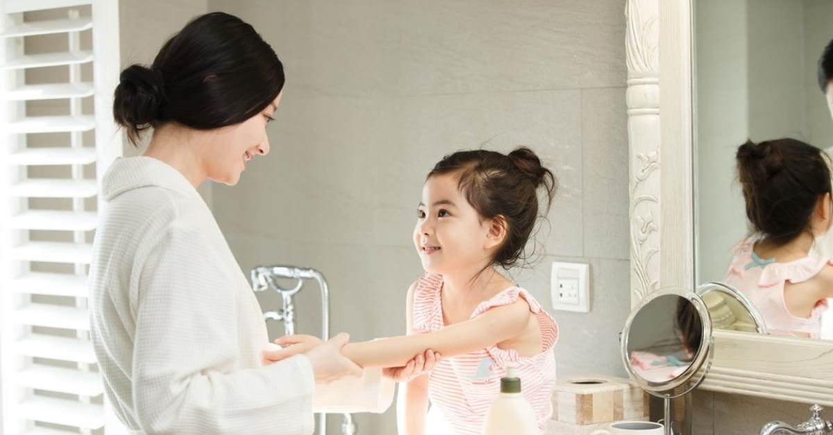 woman applying lotion to child's skin