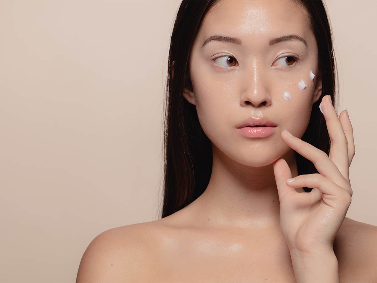 Asian woman with black hair and white dots of cream on her cheek