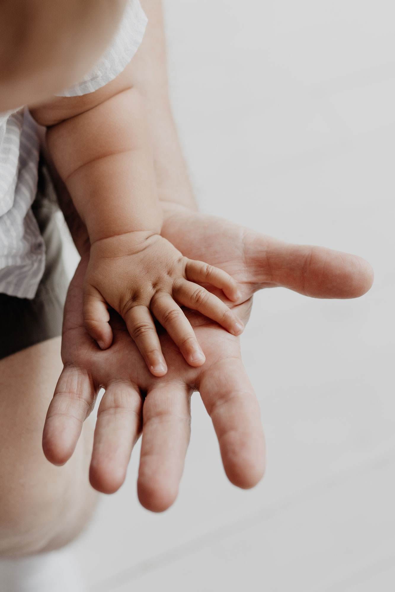 Cropped image showing a white woman's hand holding a baby's hand