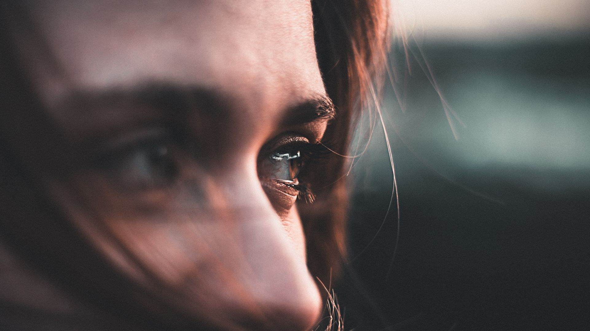 Close up on a white woman's eyes. She has brown eyes and brown hair and is looking to the right in an enigmatic way.