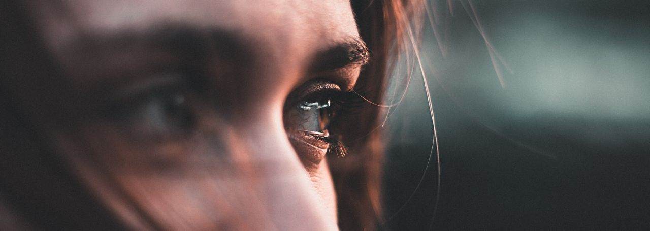 Close up on a white woman's eyes. She has brown eyes and brown hair and is looking to the right in an enigmatic way.