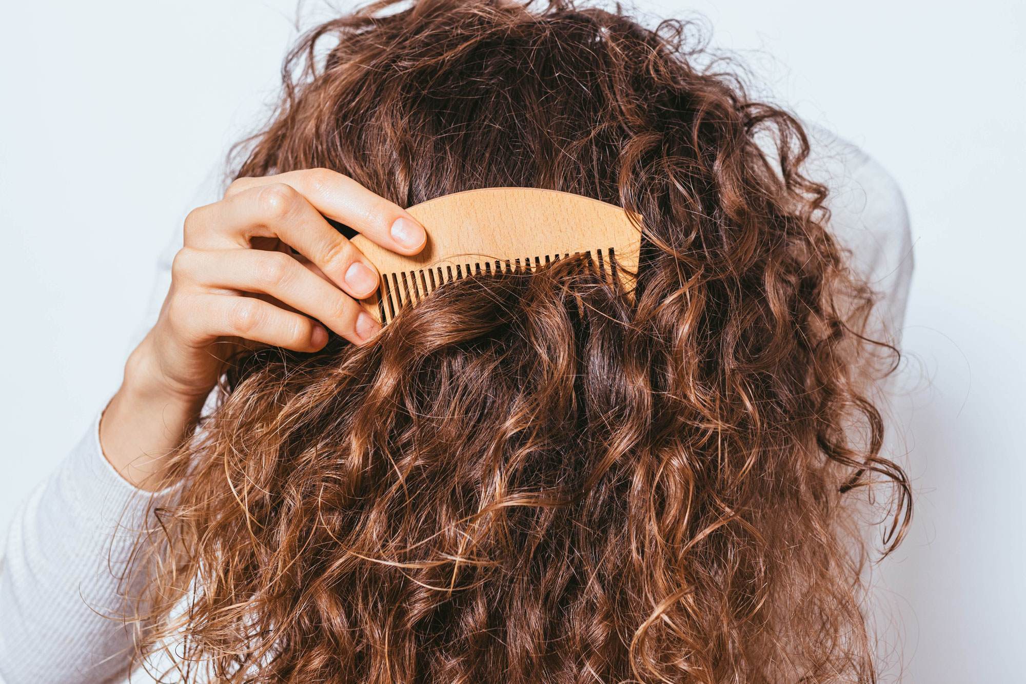 Girl with light brown curly hair running comb through it