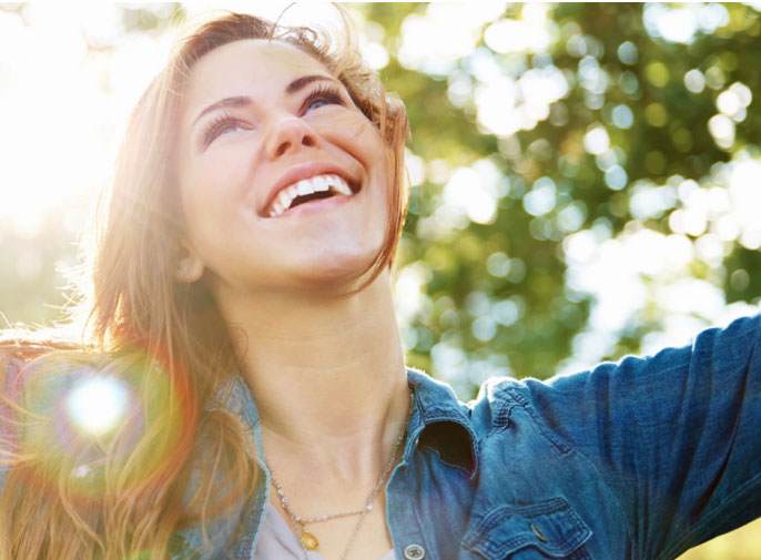 Girl with blonde hair smiling in the sunlight.