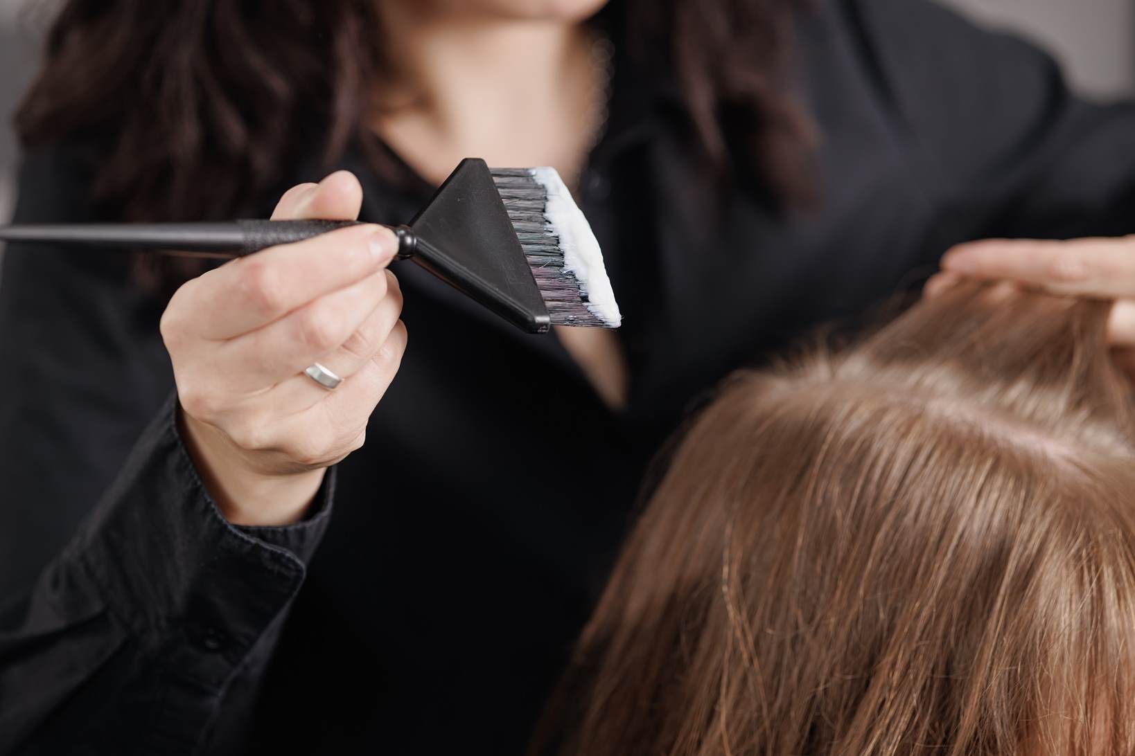 Colouring hair Hairdresser applying hair colour to roots landscape 2 female white blonde hair care				 				 				
