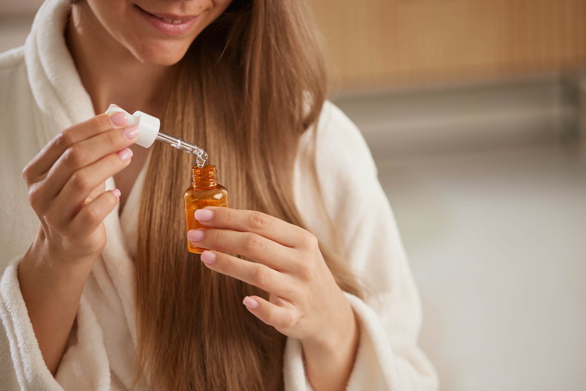 Oils for hair care Female with dropper bottle of oil portrait 1 female white blonde hair care