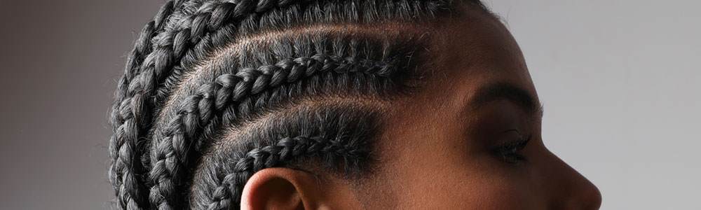 Young black woman with hair in a cornrows style. Cropped image with her looking to the right, we only see her eyes, nose and hair.
