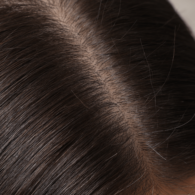 Close up on the scalp and roots of a woman with long brown hair