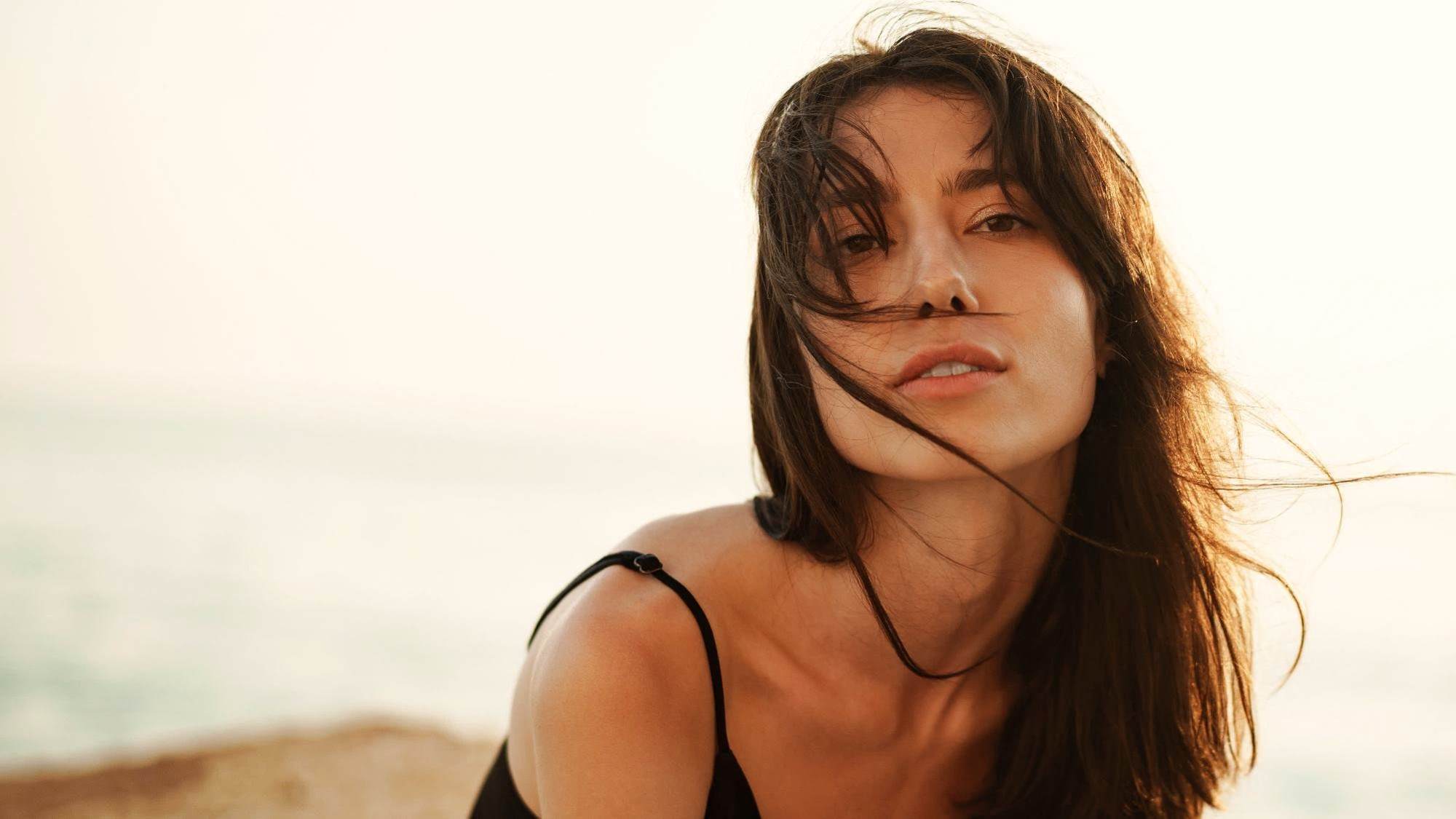woman with dark hair blowing in the breeze on the beach