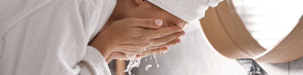 Clean beauty - Woman washing her face over sink in bathroom with water running and splashing from tap