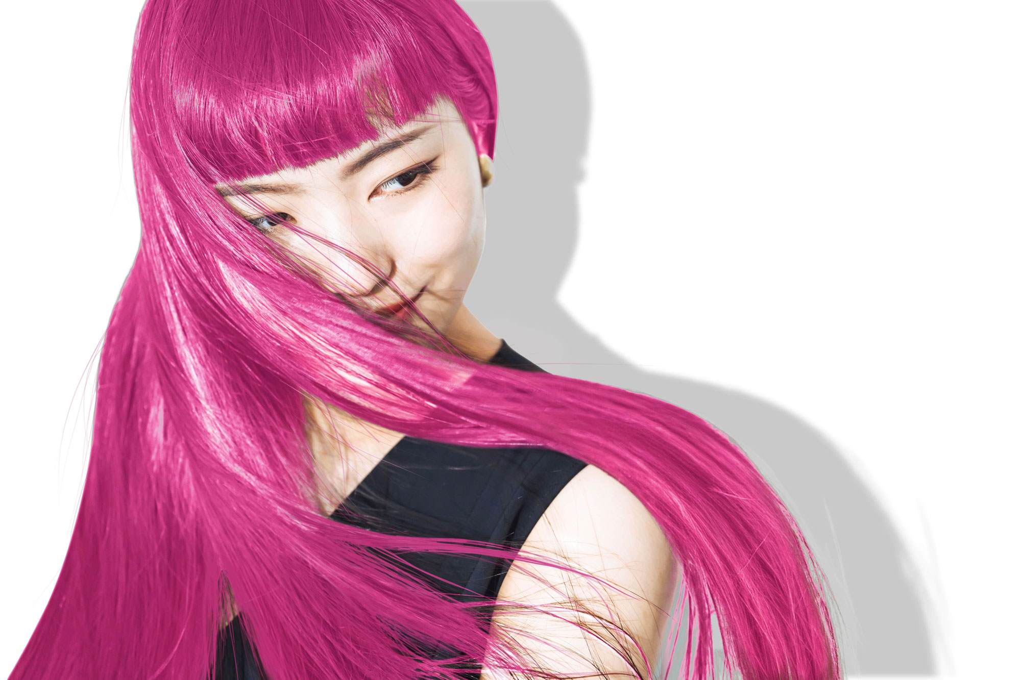 East asian woman in her 20s with long, straight, bright pink hair. She is looking to the right and smiling.