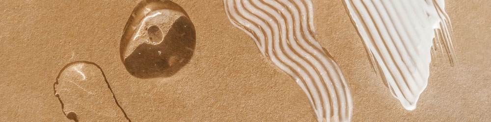 different sun care formulation textures on a sand background including gels, serum and creams