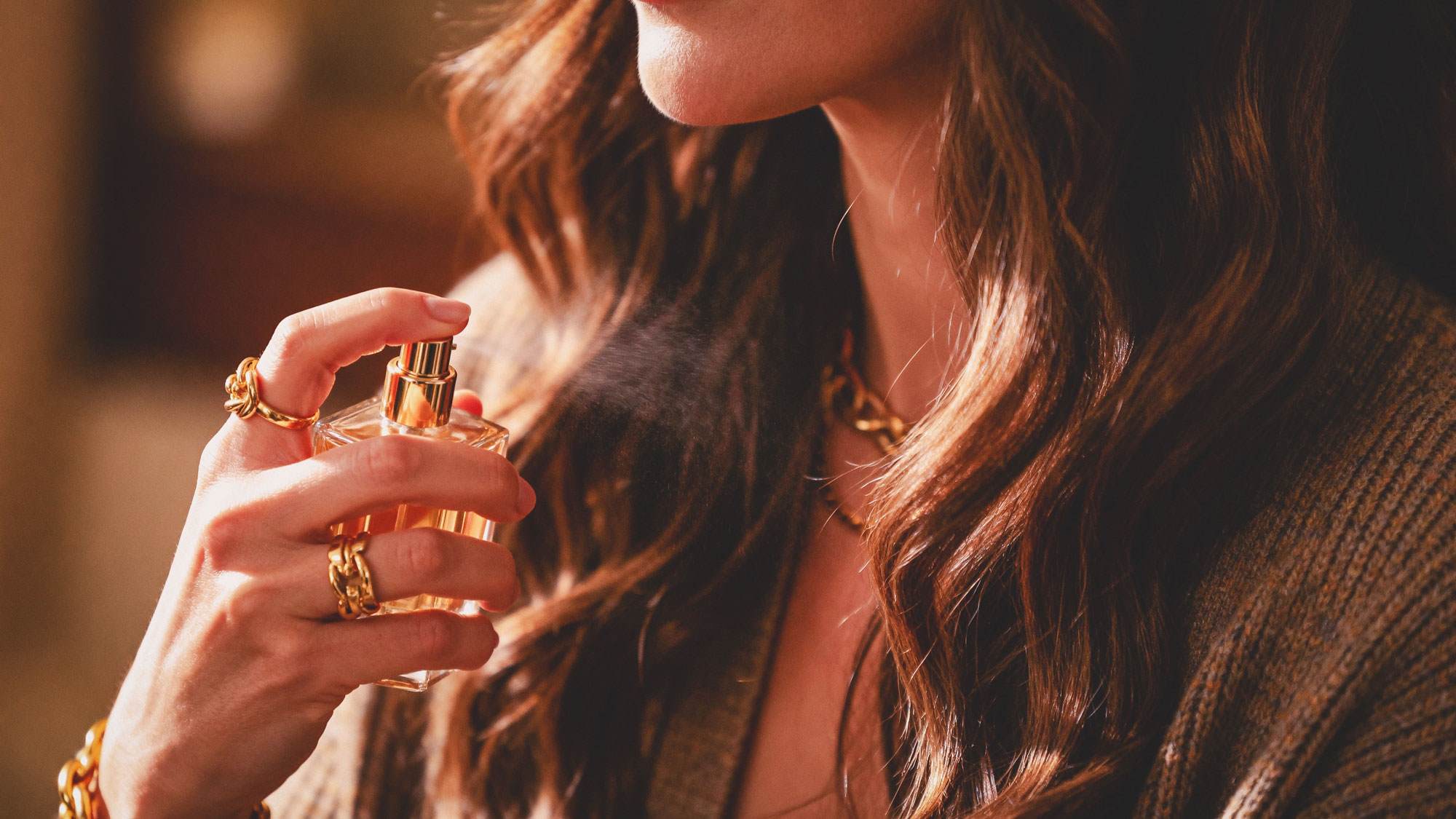 White woman spraying her brown hair with hair mist perfume