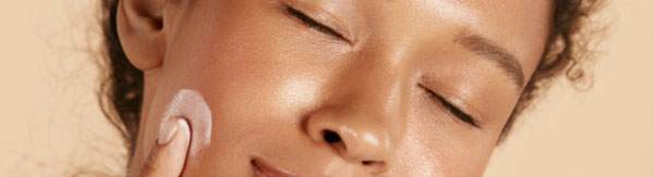 woman closing her eyes and applying a serum