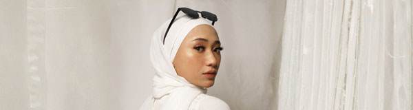 Middle eastern woman wearing a white hijab and sunglasses turning back to the camera