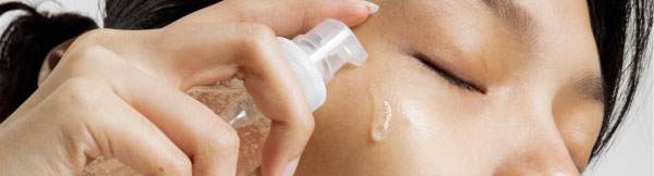 Close up on an east asian woman's eyes, she is applying a skin care serum