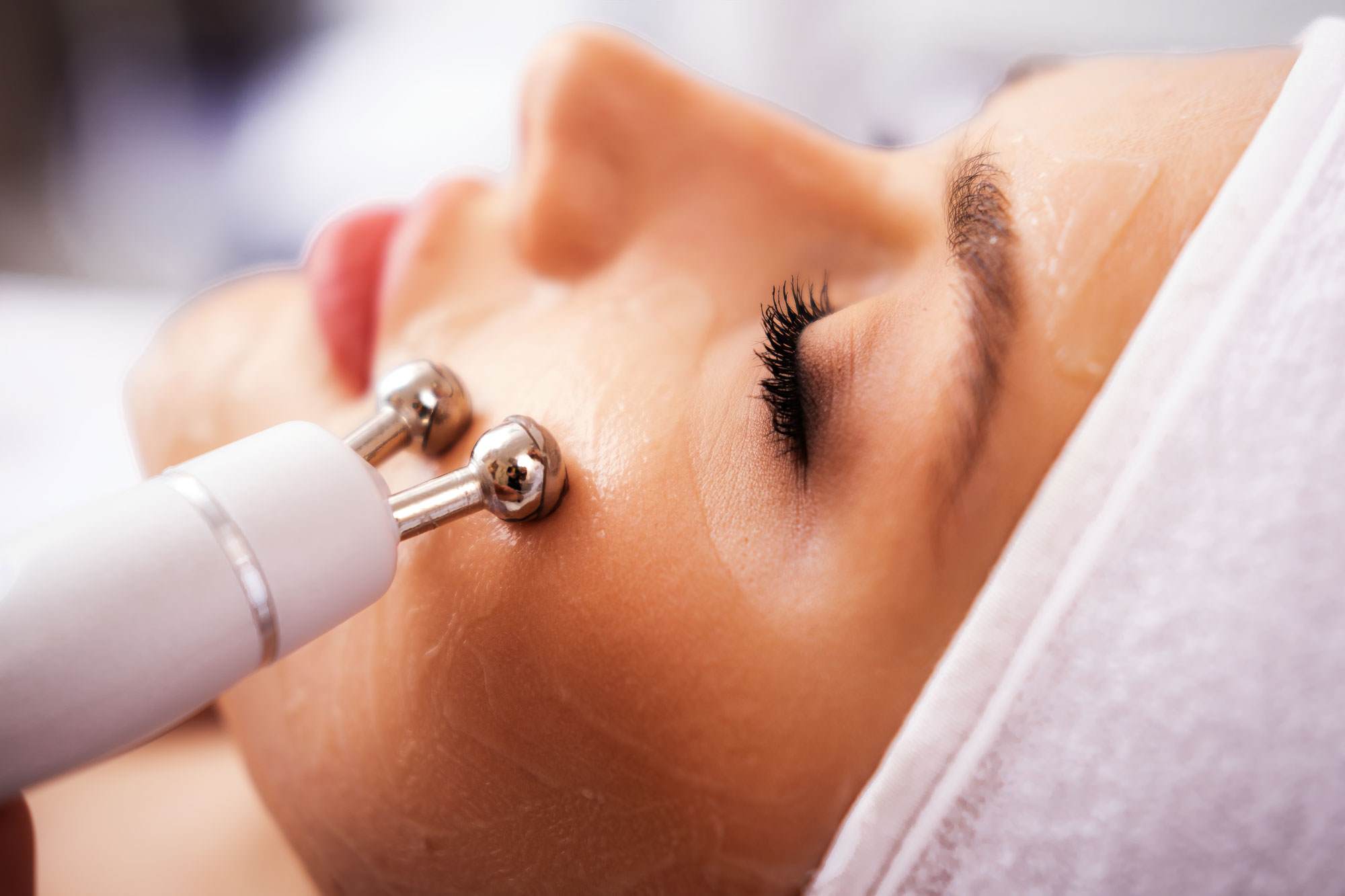 White woman with her eyes closed receiving microcurrent treatment.
