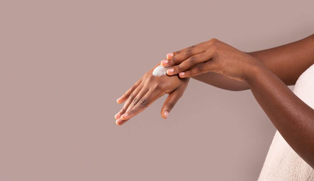 A black woman applying cream to her hands
