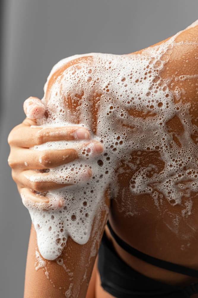 Cropped image of a white woman's shoulder covered in white foam
