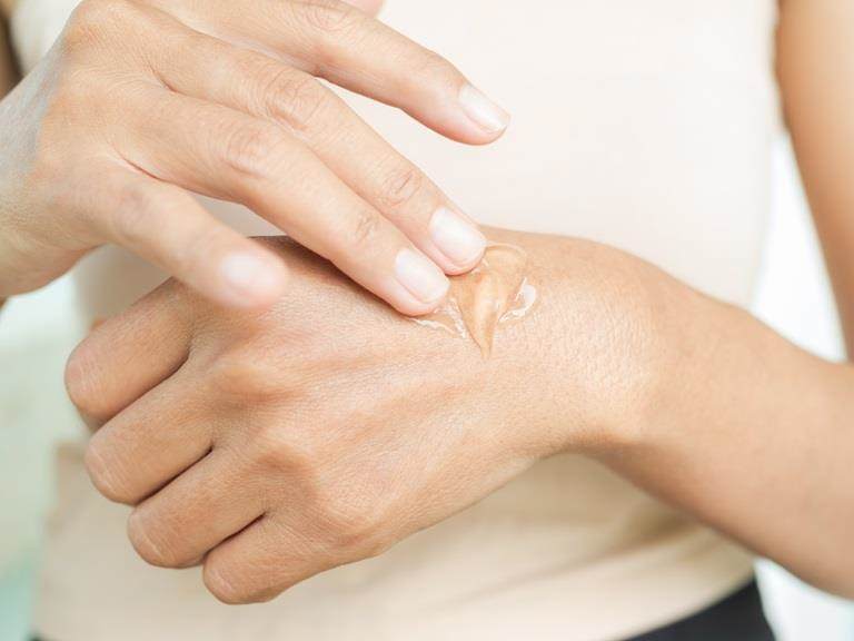 Cropped photos of a white woman's hands. She is applying a serum to her hands.