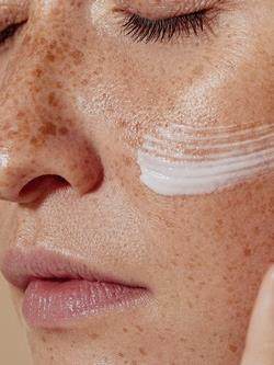 female applying cream to skin