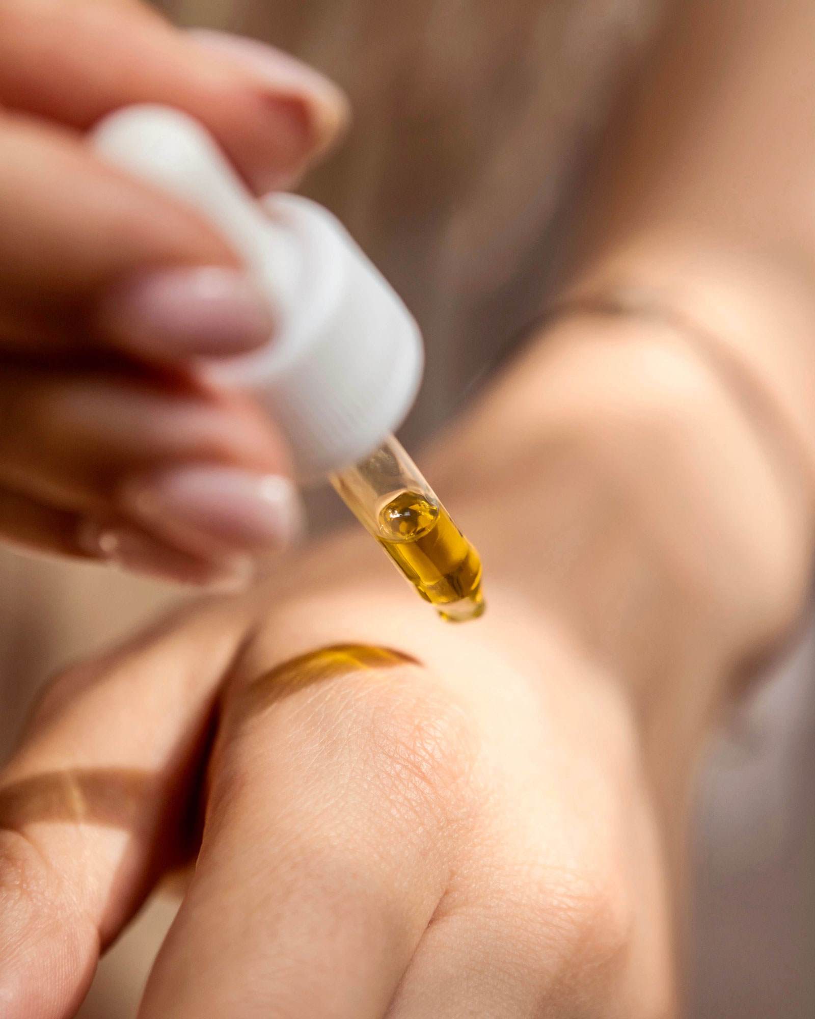 オイルをスポイト瓶から手に塗るクローズアップ