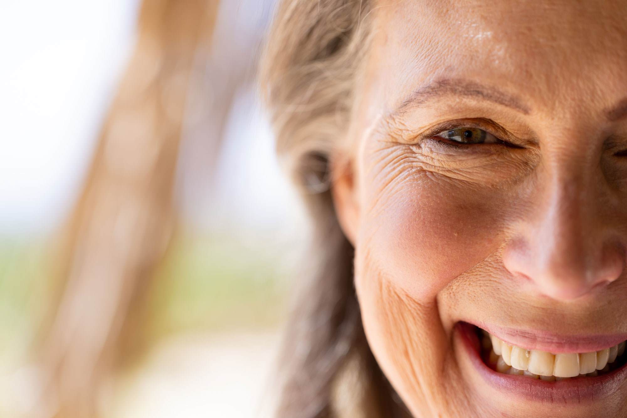 barrier strengthening face cream - cropped close up of older woman smiling.