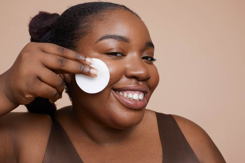 Smiling black woman removing her make-up