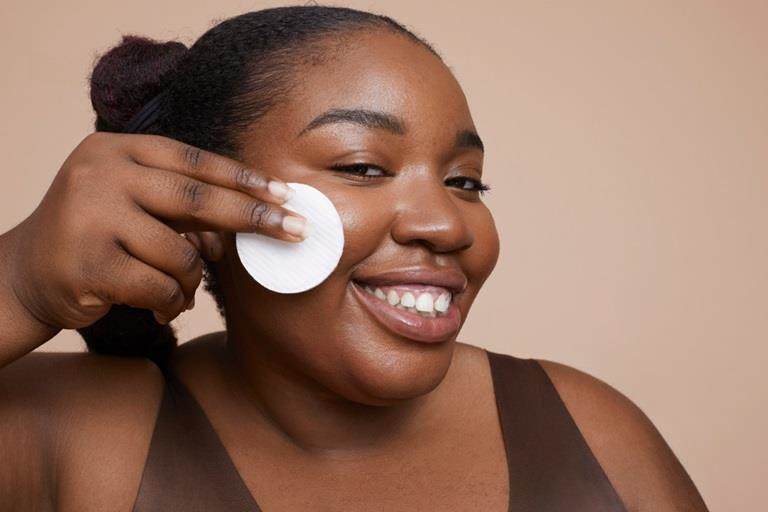 Smiling black woman removing her make-up