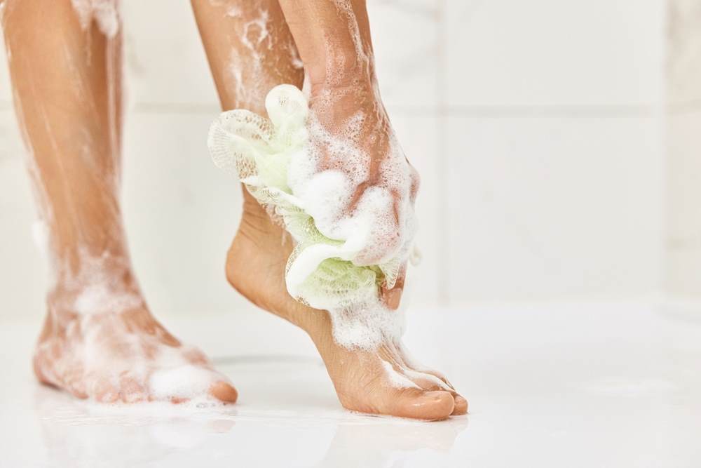 Cropped image of a white woman's foot applying body wash