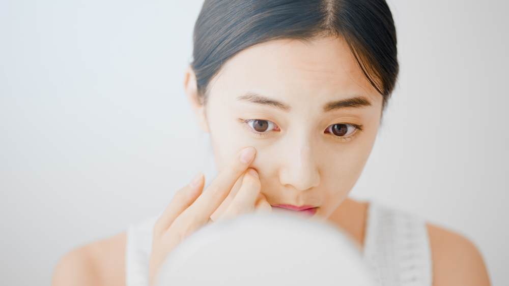 Ceramide feather veil eye emulsion - young east asian woman applying lotion underneath her eye