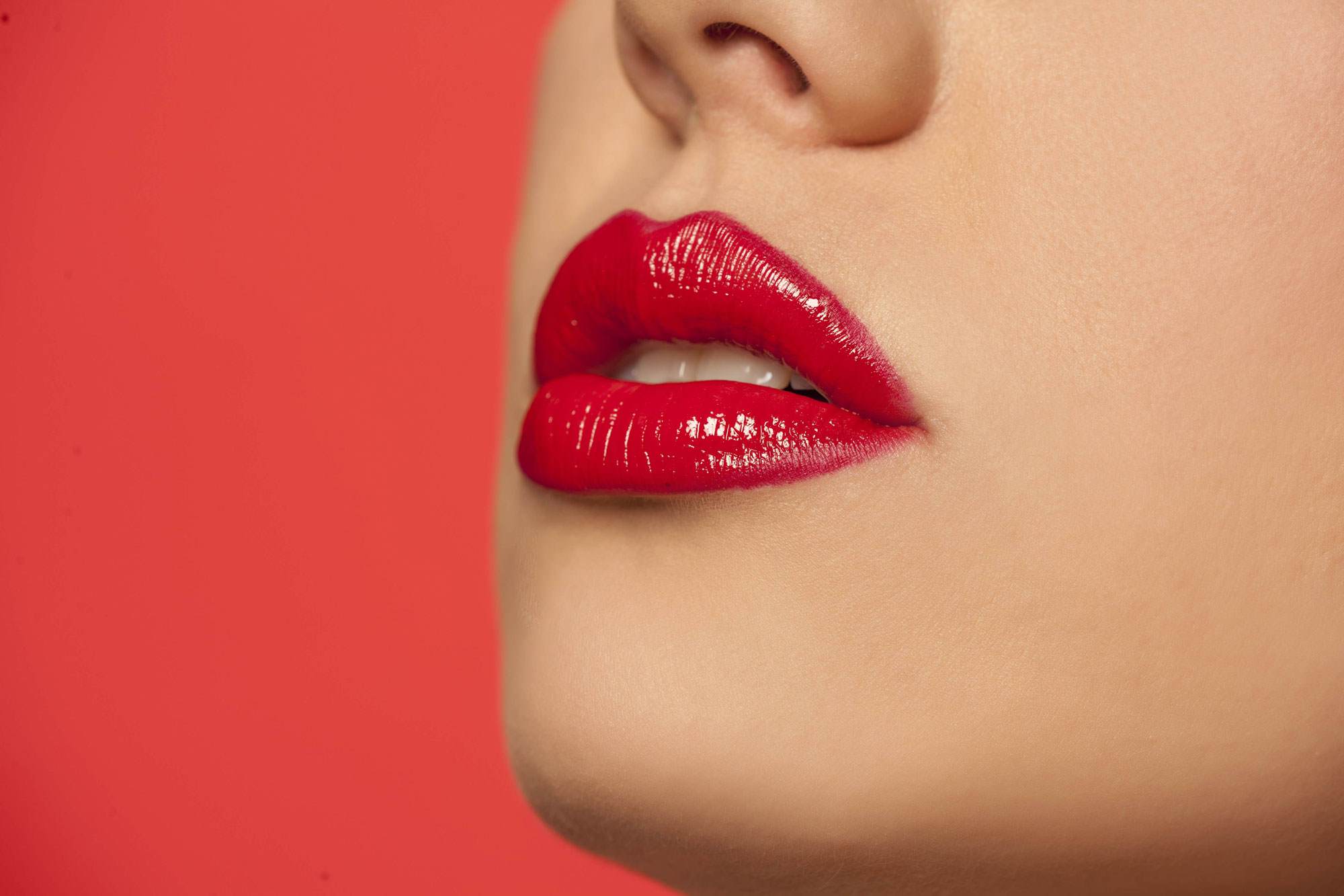 Cropped image of a young white woman's lips. She is wearing bright red lipstick.