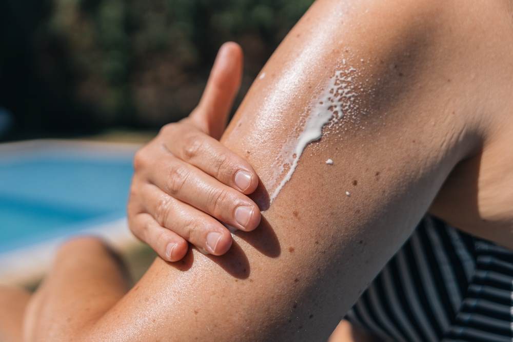 Close up on a white woman's shoulder as she applies sunscreen