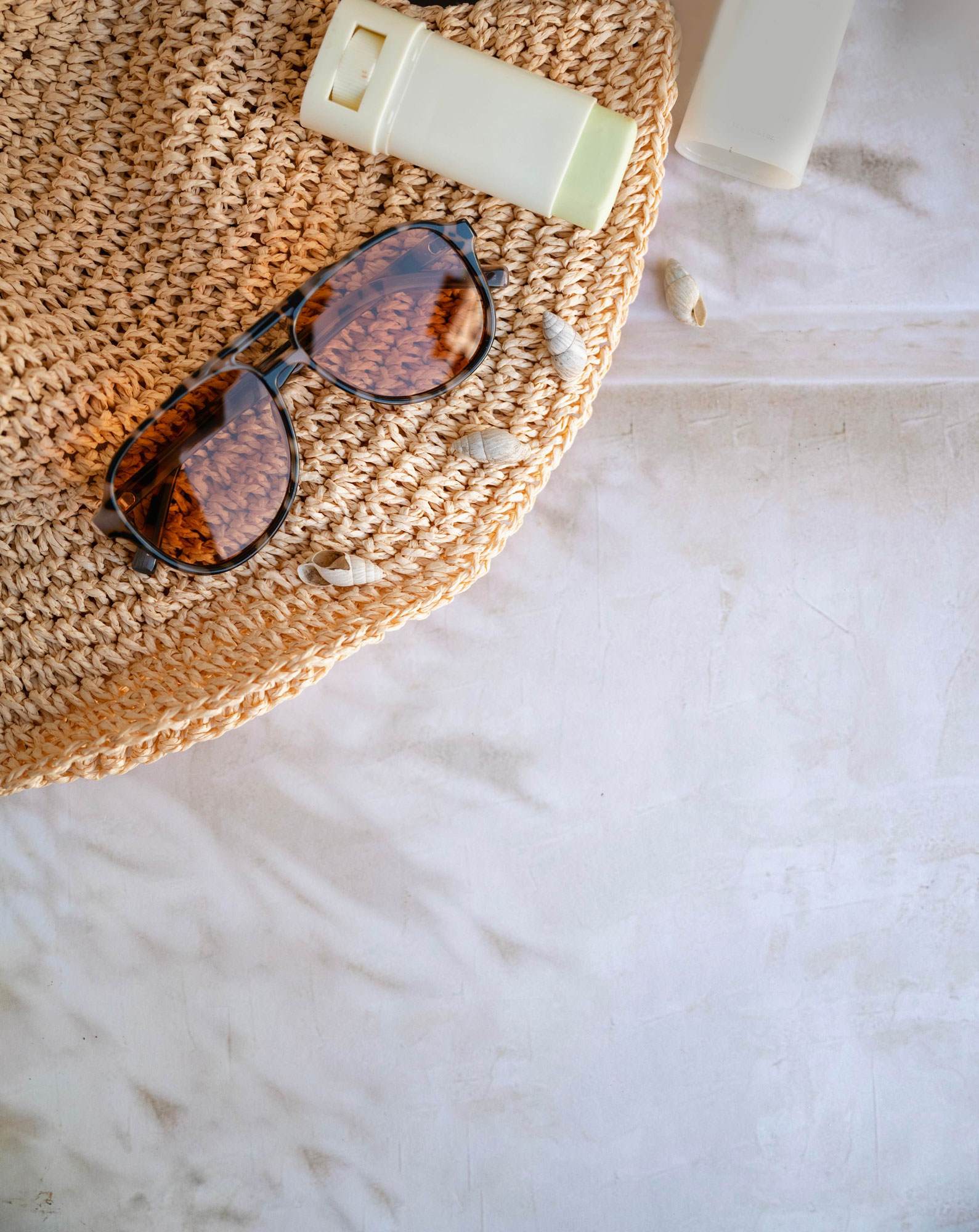 Natural skin brightening mineral sunscreen stick with sunglasses and sun hat.
