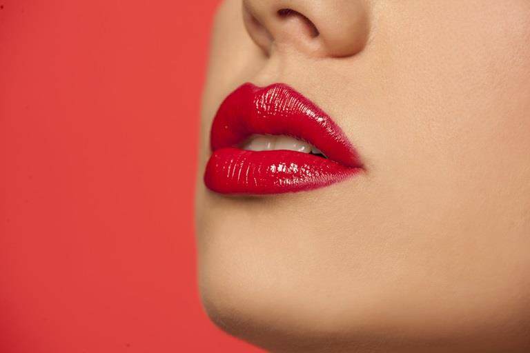 Cropped image of a young white woman's lips. She is wearing bright red lipstick.