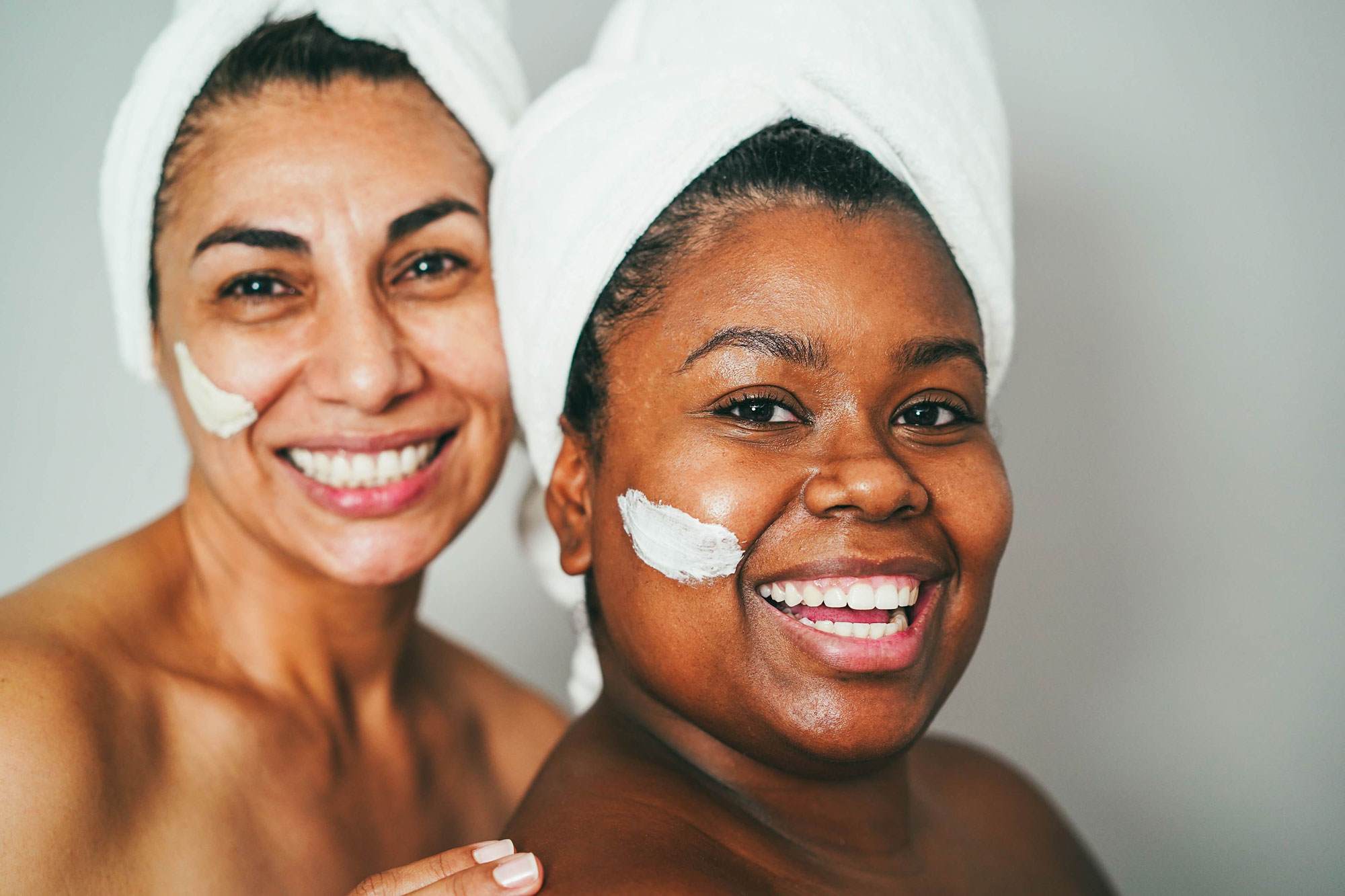 2 women smiling with lotion on their face