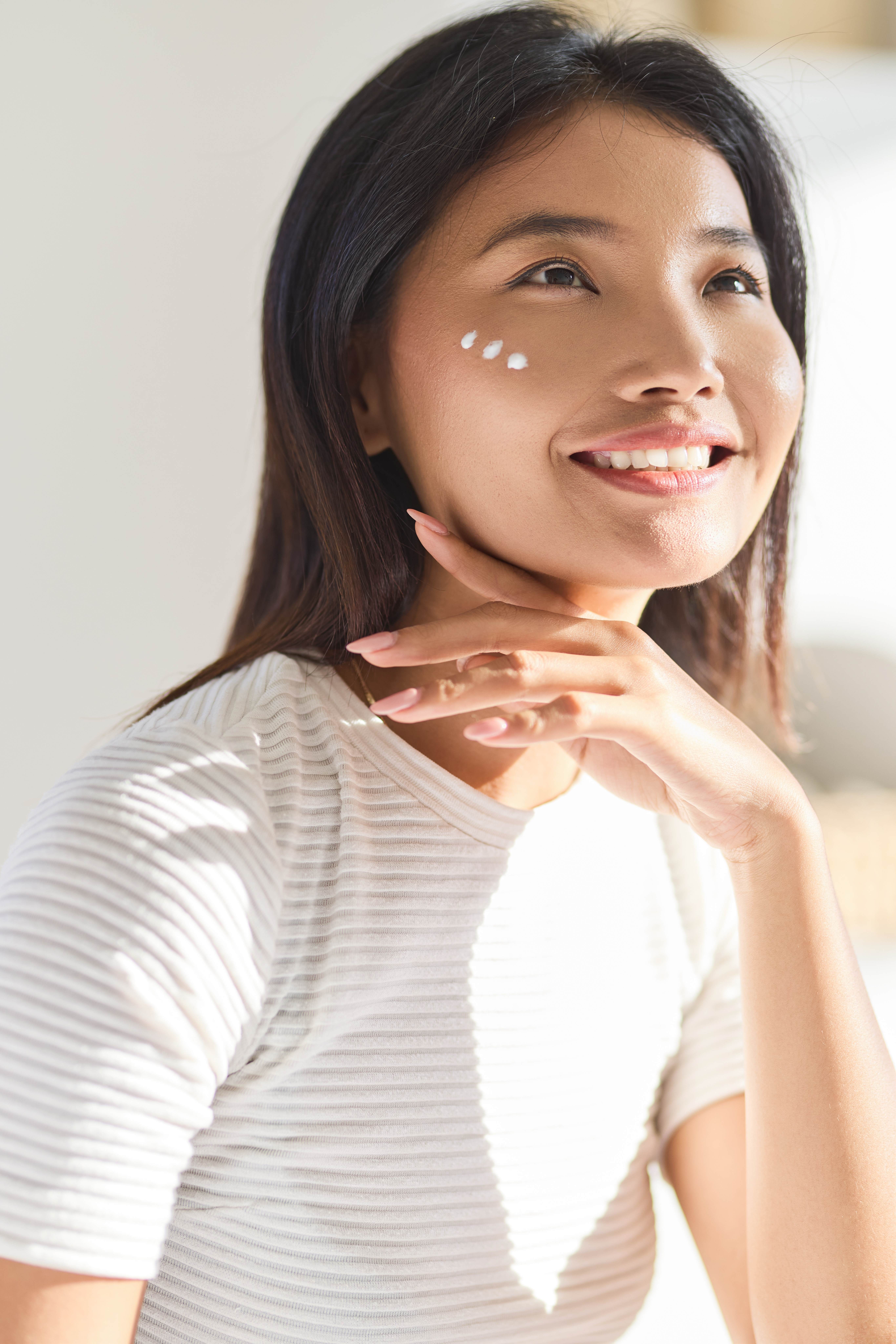 Woman with dots of lotion on her cheek