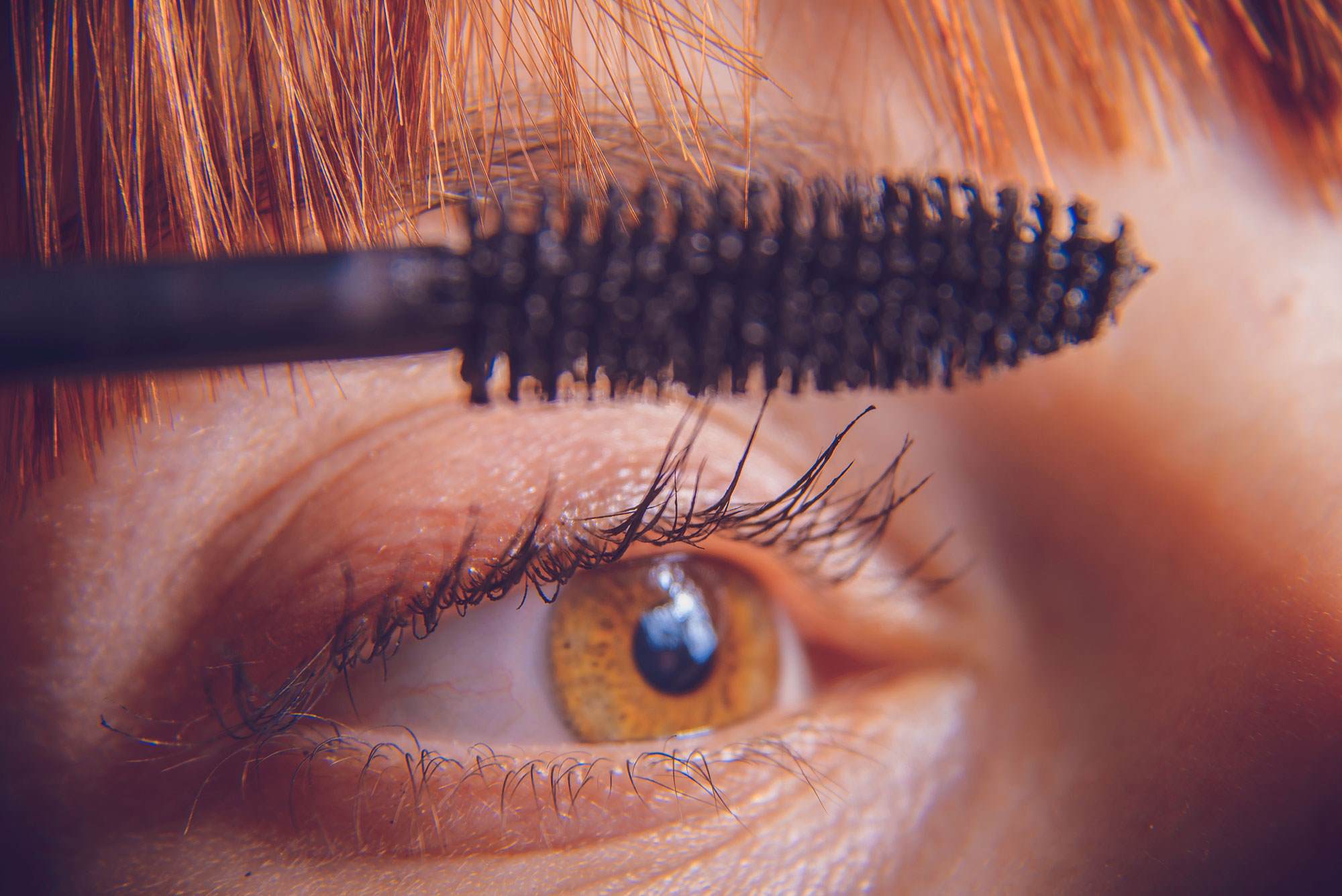 strength and growth revitalising mascara close up on woman applying mascara to eye