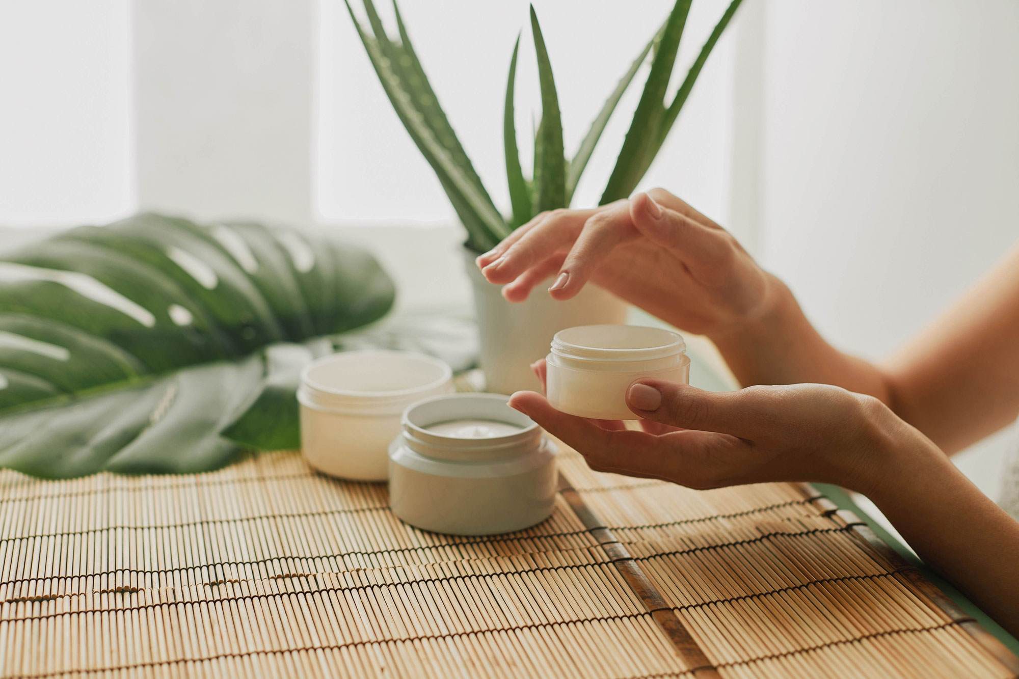Female hands holding a beauty cream on a relaxing natural background
