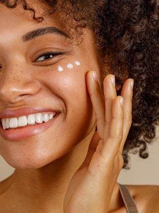 woman applying white face cream in dots across face