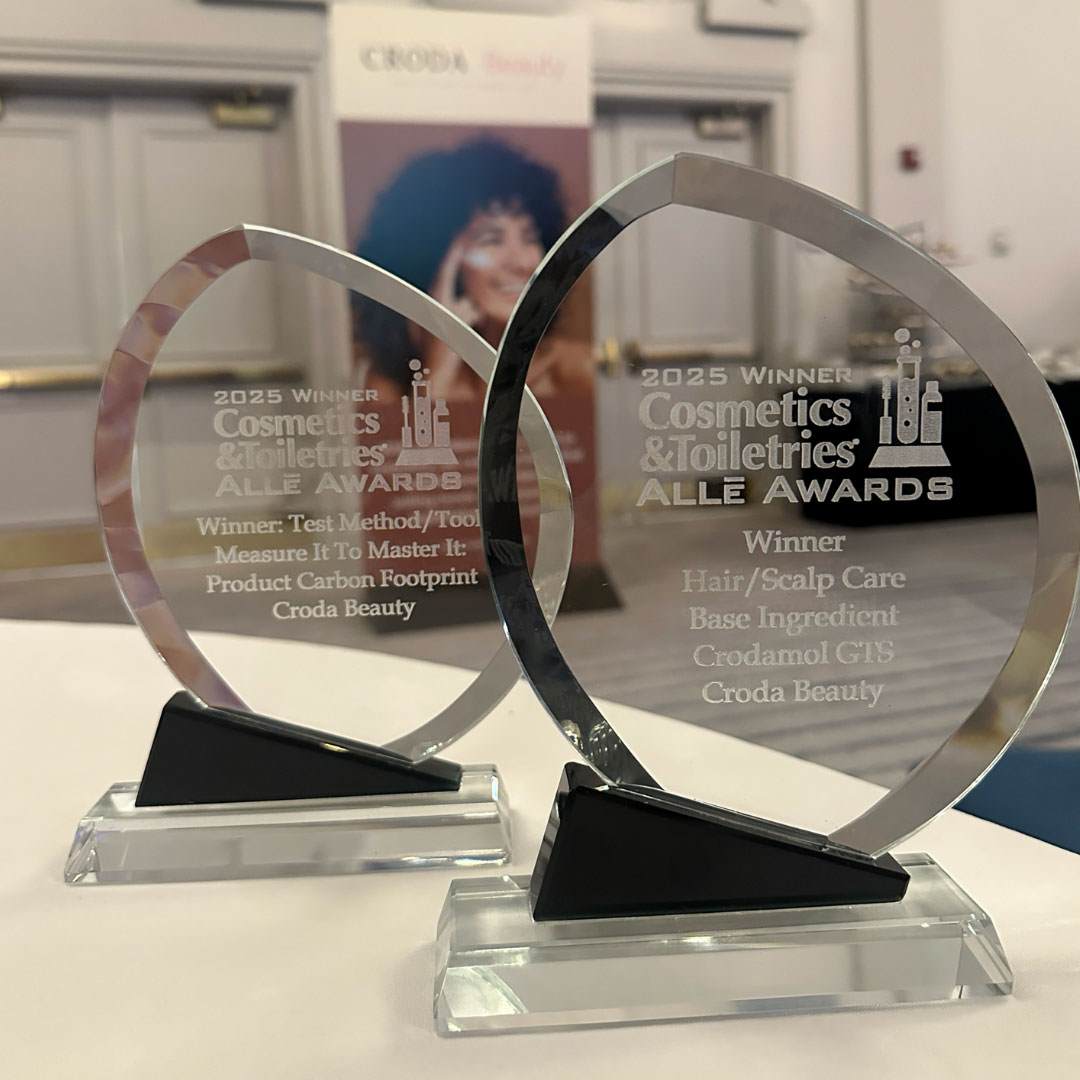 Photograph showing 2 glass awards, the Crodamol GTS won the Cosmetics & Toiletries® Allē Awards 2025. One award reads "Winner: test Method/Toolkit Measure It To Master It: Product Carbon footprint Croda Beauty." the other reads "Winner:  Hair/Scalp Care Base Ingredient Crodamol GTS Croda beauty