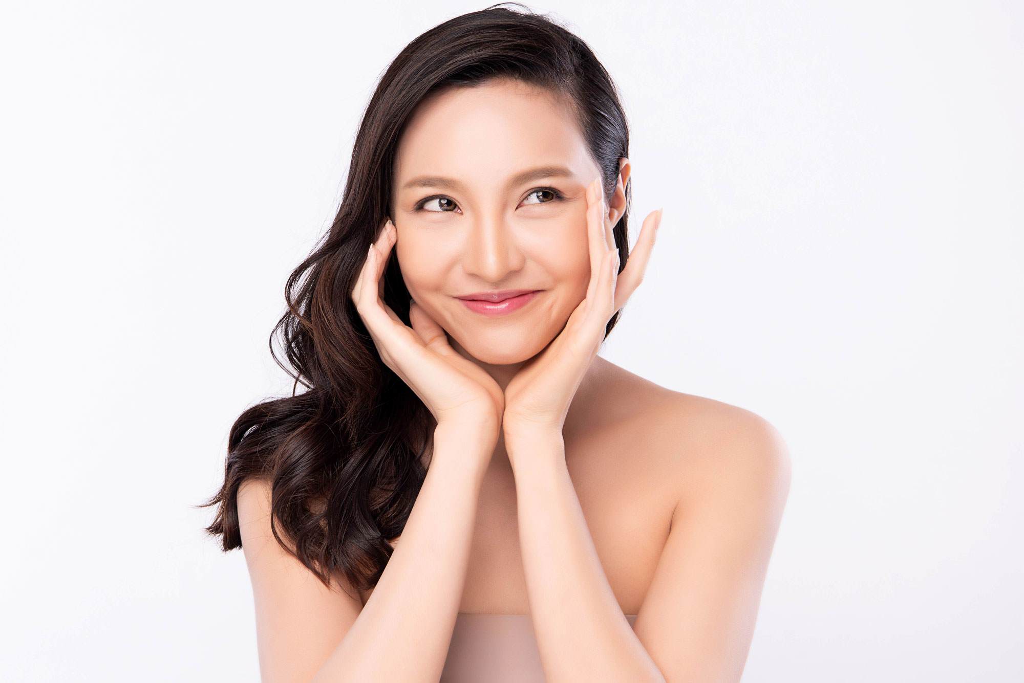 Matrixyl synthe 6 smiling young east asian woman with black hair touching her hands to her face.