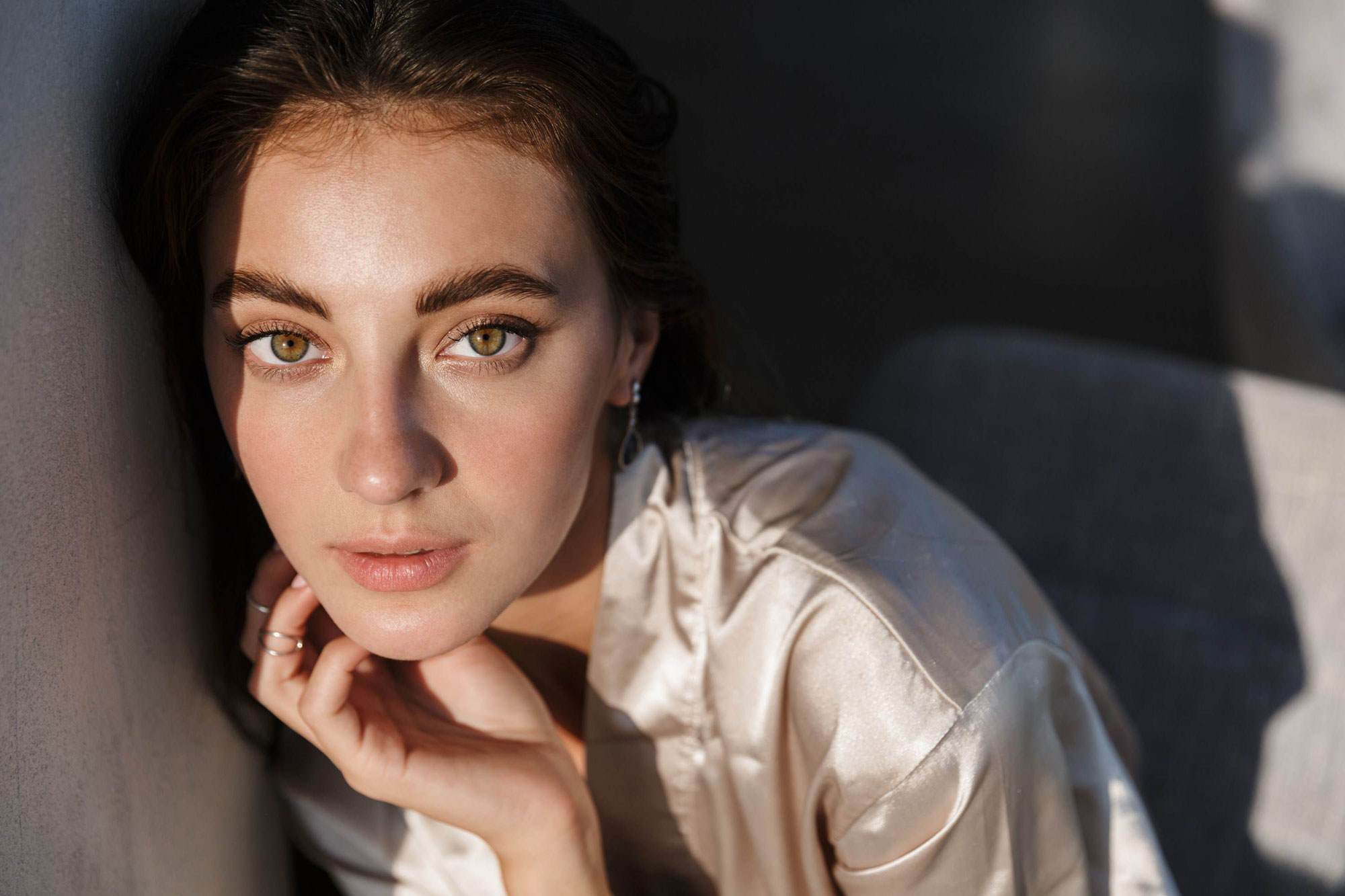 Woman with hands at her chin looking towards camera