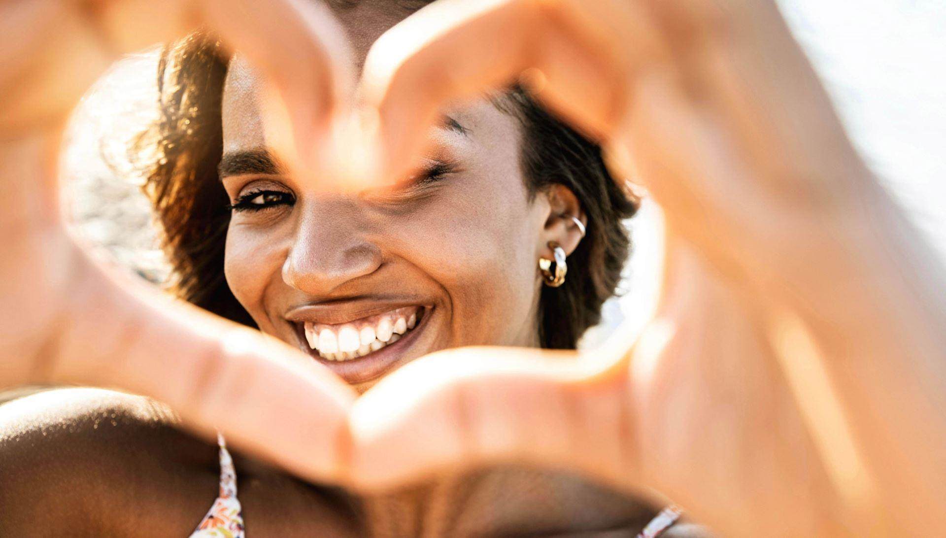 woman in the sunshine making heart with hands