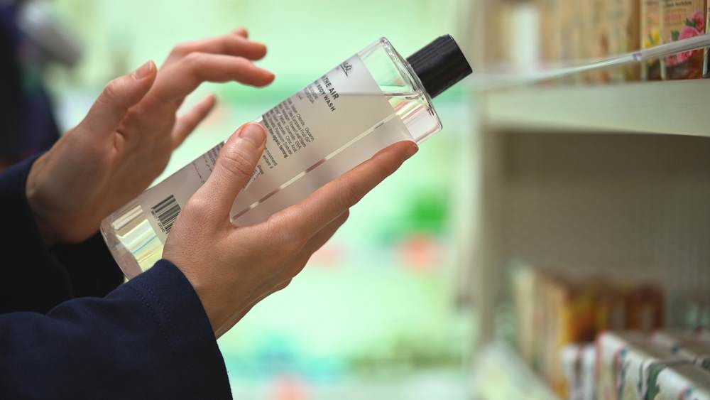 Cropped image of the hands of a woman reading the ingredients on a shampoo bottle