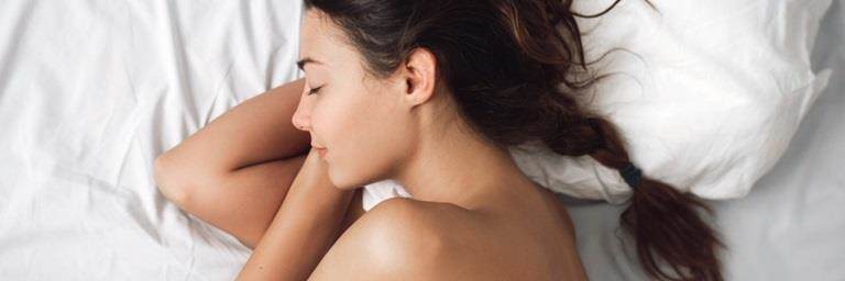 Young white woman with brown hair sleeping on a bed