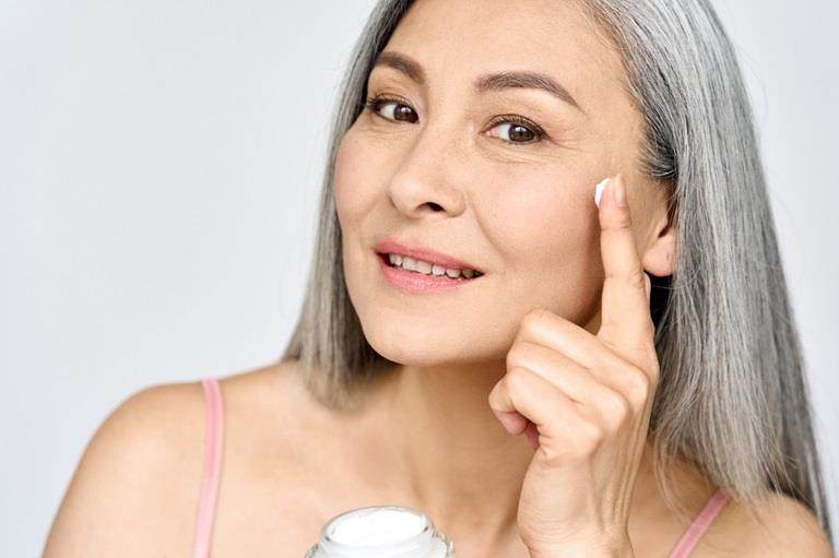 Older east asian woman applying cream to her face