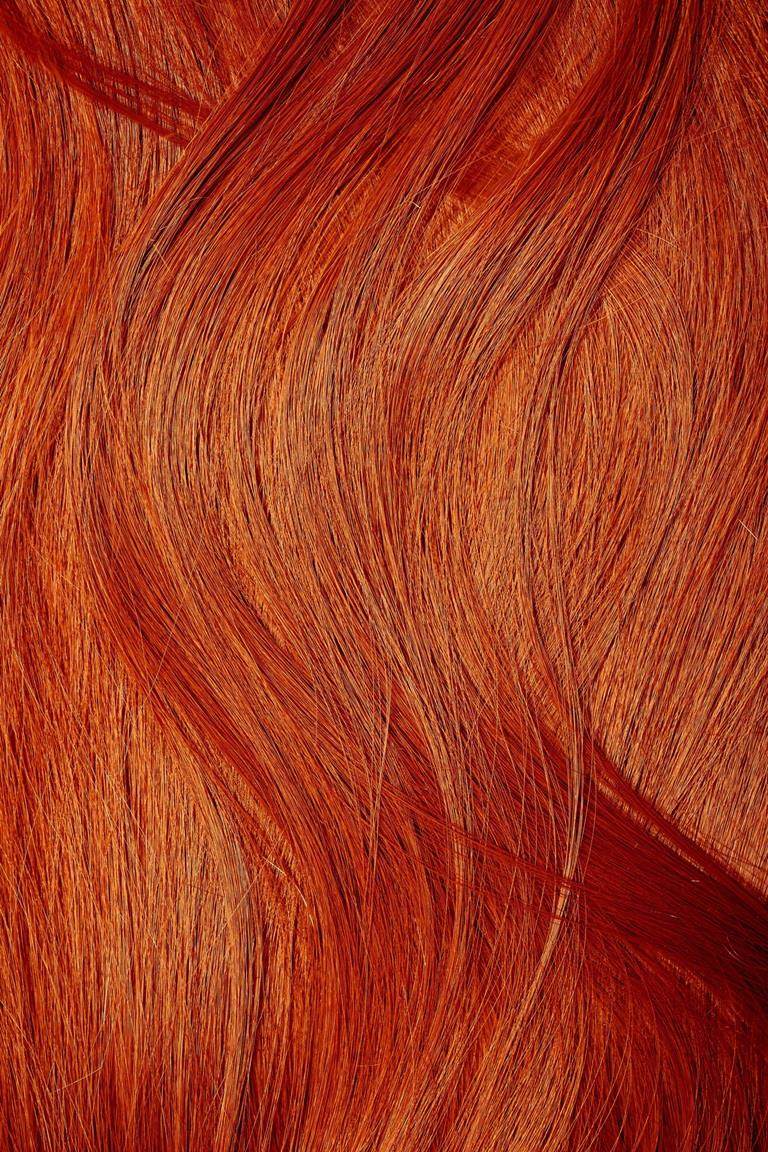 Extreme close-up on bright orange straight hair.