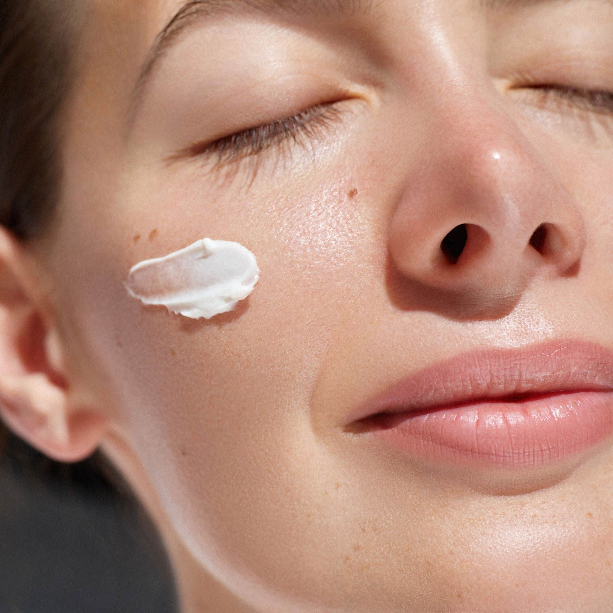 spf boosters - white woman smiling in the sun with cream on face