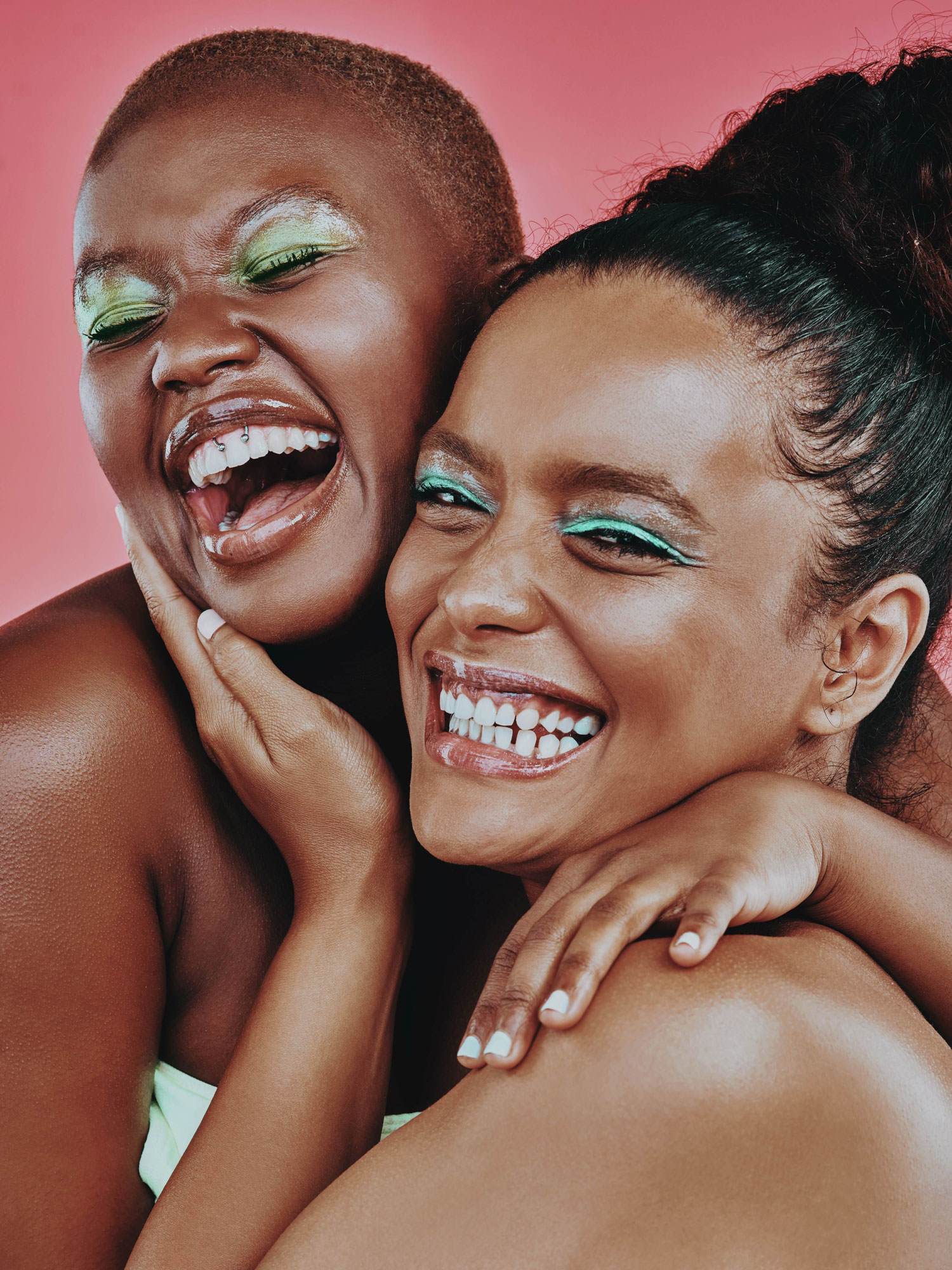 two women with big smiles and colourful makeup